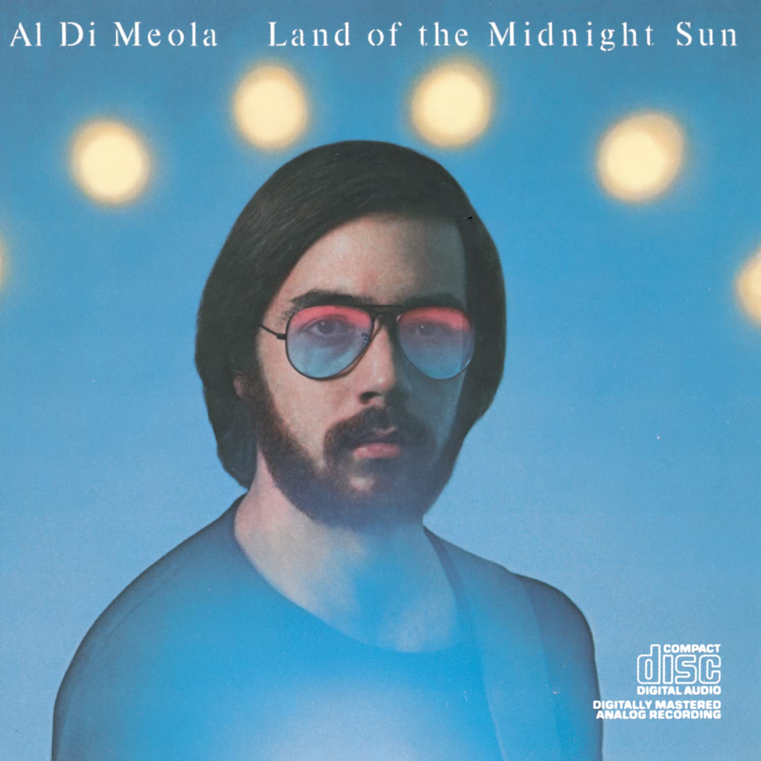 Al Di meola album "Land Of The Midnight Sun" he is shown in front of a light blue background with what appears to be the trajectory of the sun